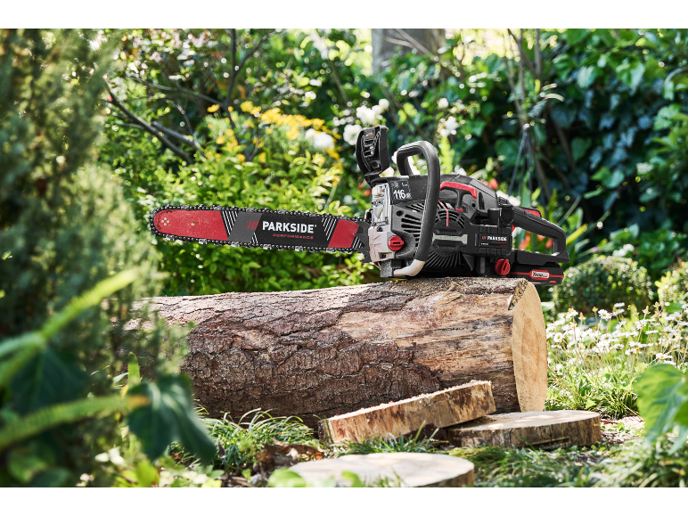 Chainsaw on a tree log outdoors, with a green background.