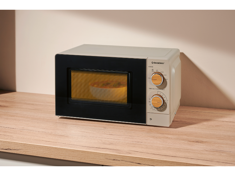 Beige microwave with wooden details, on a wooden kitchen countertop.