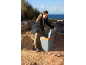 Woman opening a portable electric cool box on a rocky coastal path.