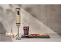 Gold immersion blender with whisk, measuring cup with berries, and kitchen towel.