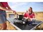 Woman cooking on a portable gas stove on a folding table while camping.