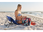Woman on a beach with a beach bag and a folding chair.