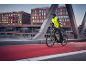 Man in a reflective vest and helmet rides a bicycle on a red bike path.