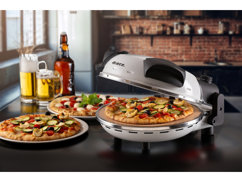 Electric pizza oven with freshly made pizzas and drinks in a kitchen setting.