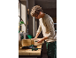 Man assembling a wooden box with a screwdriver in a workshop.