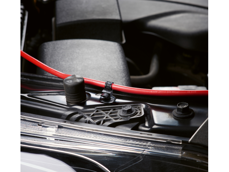 Red car battery cable secured on the engine.