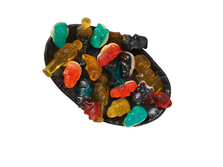Halloween gummy candies in various spooky shapes like skeletons, skulls, and bats on a black plate.