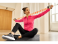 Woman in pink and black activewear exercising with a resistance band.