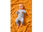 Baby in a grey ribbed two-piece set on an orange blanket