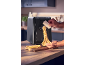 A person making fresh pasta with a black pasta machine in a kitchen.