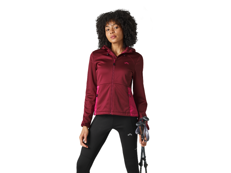 Woman in a maroon hooded jacket and black leggings holding trekking poles.