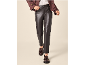 Woman in dark leather trousers, brown jacket, and tassel loafers