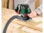 Man using a wood router with a vacuum cleaner attachment on a workbench.