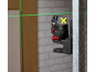 Green laser level projecting horizontal and vertical lines on a construction site.