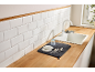 Kitchen counter with white sink, faucet, and dish drying mat with plates and cutlery.