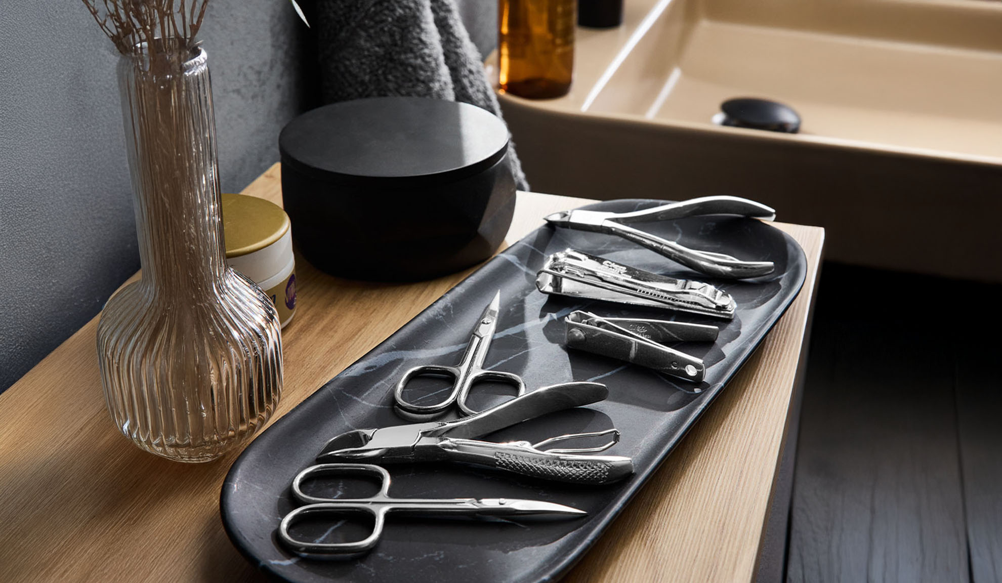 Manicure and pedicure tools on a tray by a sink.