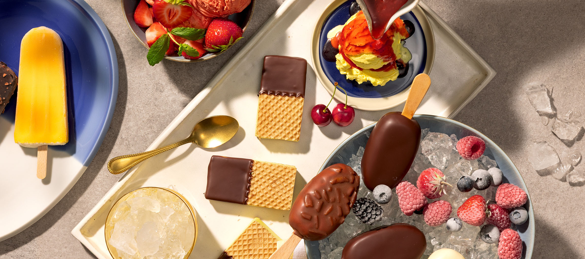 Assortment of ice cream bars, ice cream scoops, and chocolate-dipped wafers with berries.