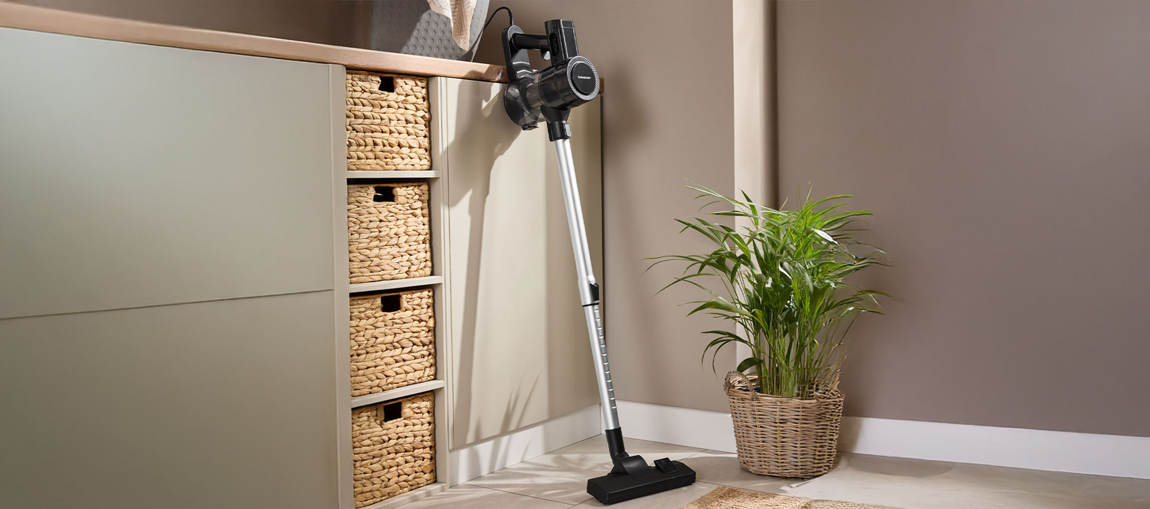 Vacuum cleaner in a modern room with wicker baskets and a green plant.