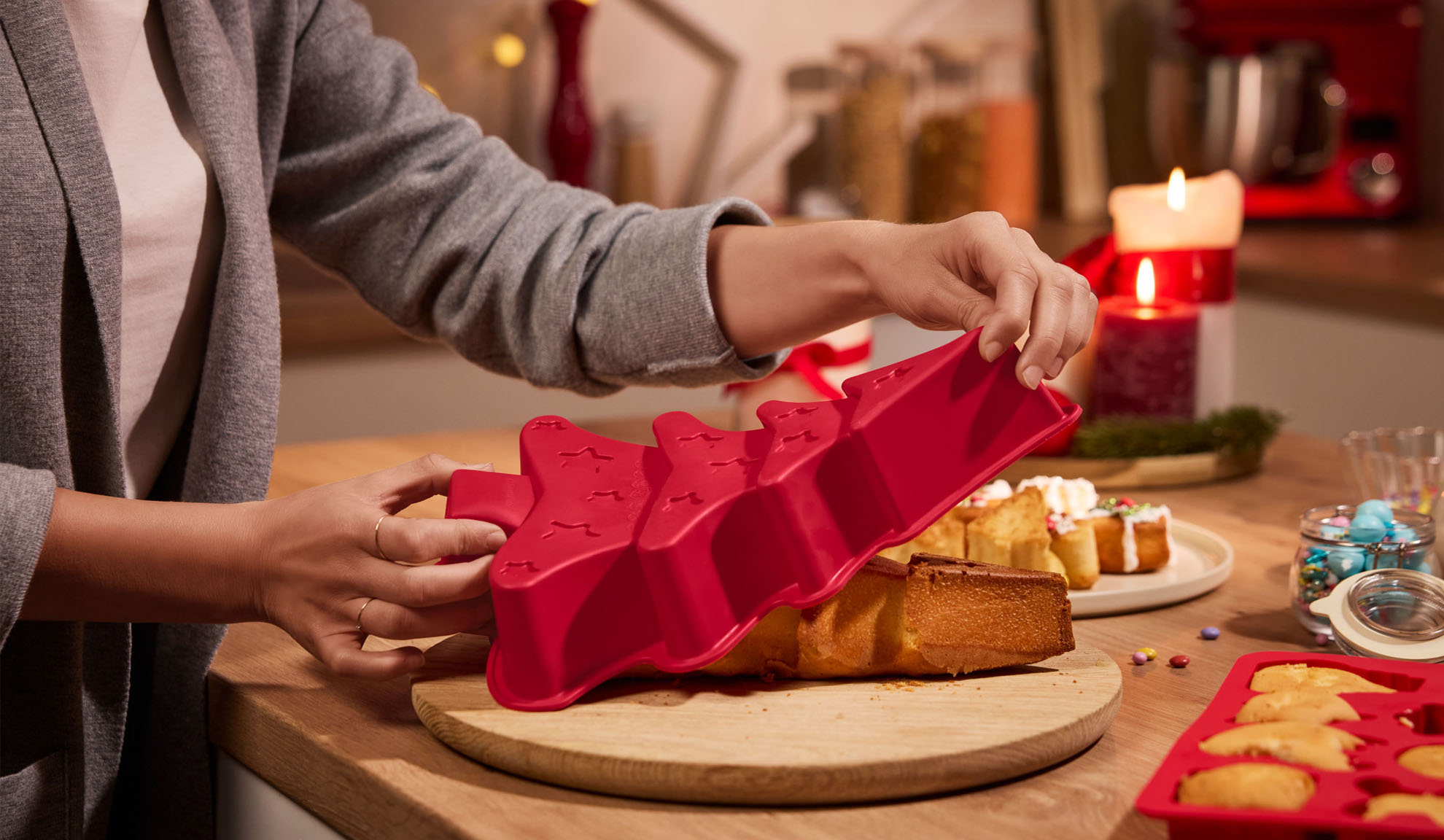 Hands removing a Christmas tree cake from a red silicone mold.