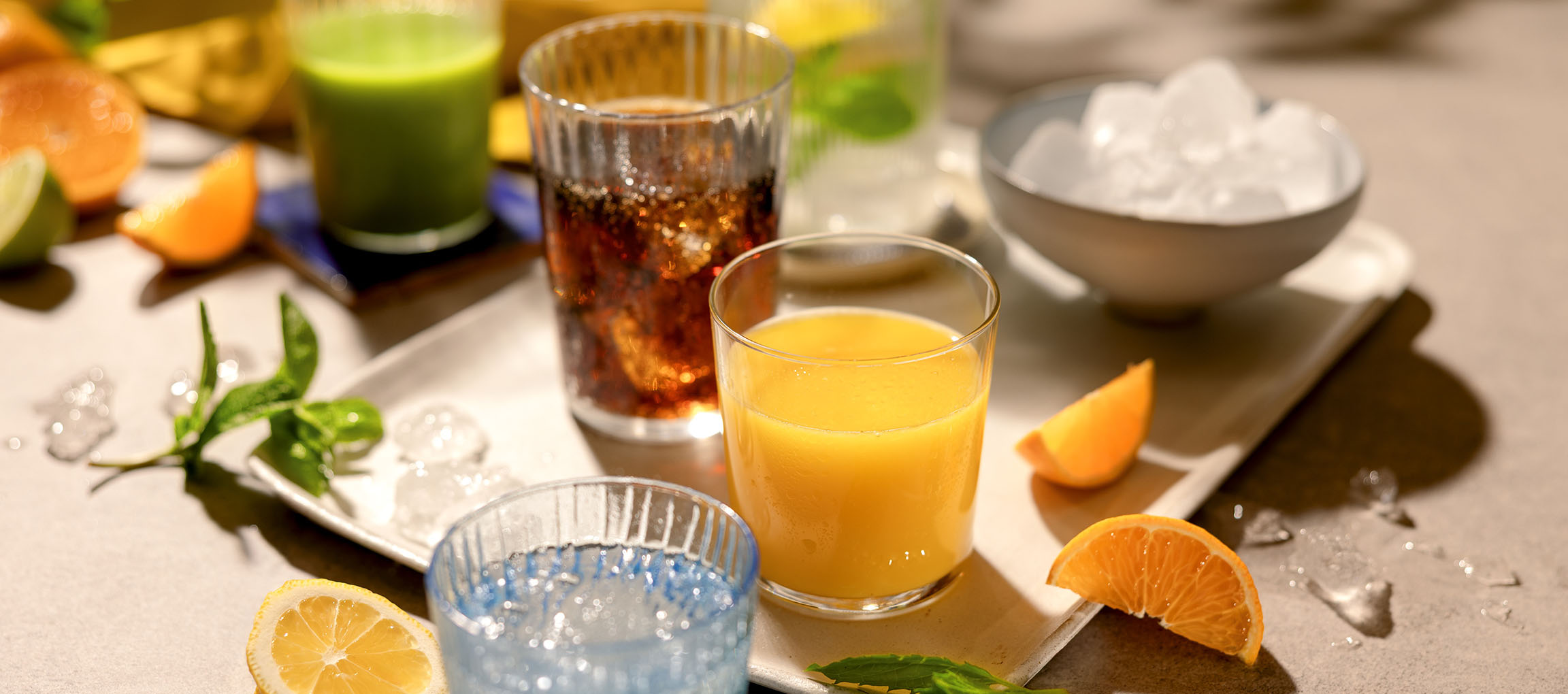 Various refreshing drinks and fruits on a tray, including orange juice and fizzy drinks.