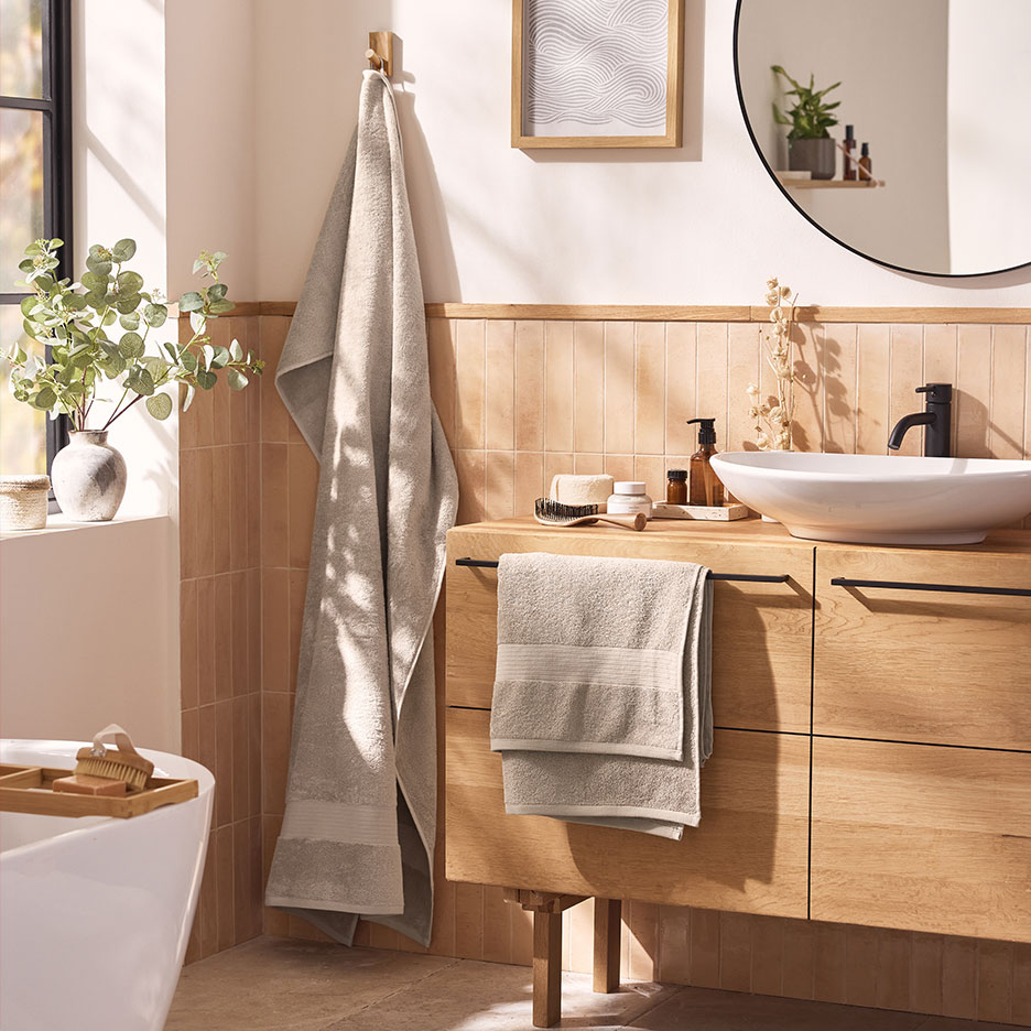 Modern bathroom with beige towels, white sink, and wooden furniture.