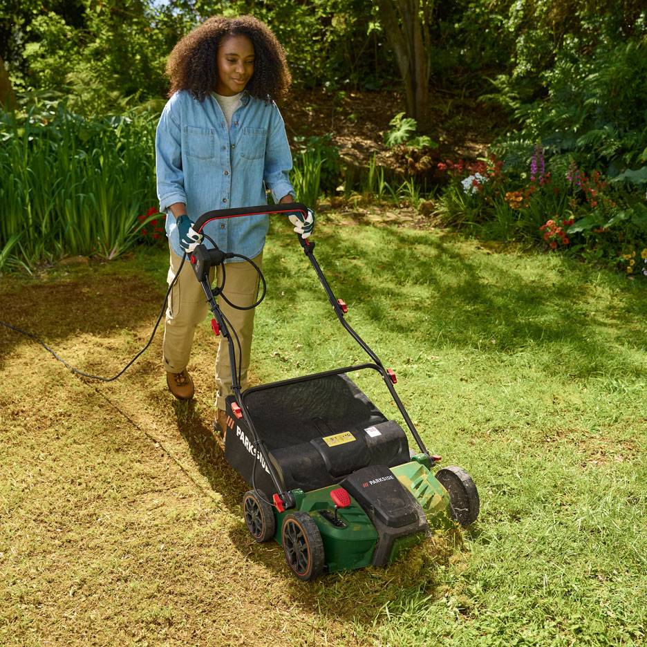 Woman using an electric lawn scarifier in a garden.