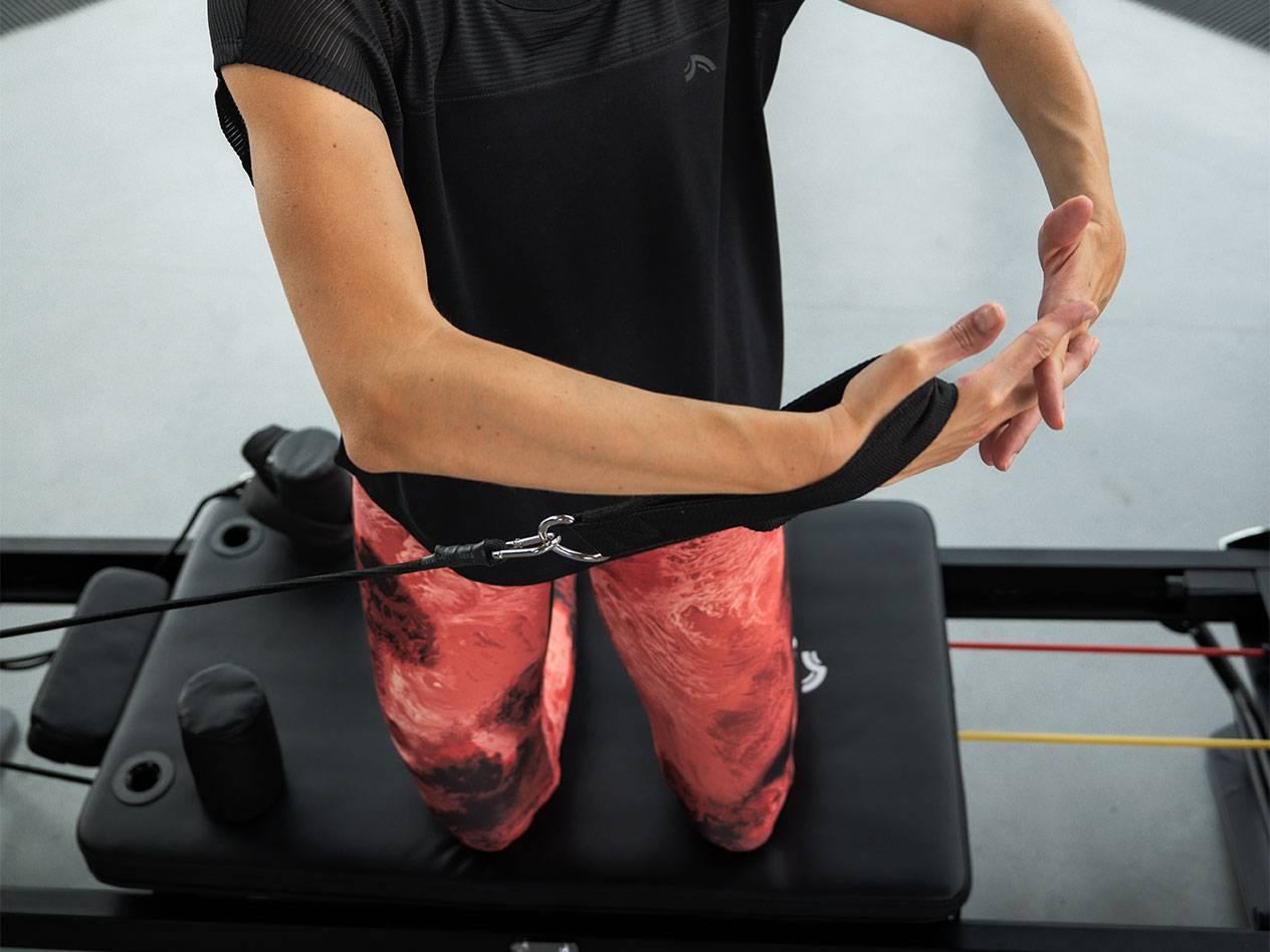 Woman exercising with resistance bands on a Pilates machine.