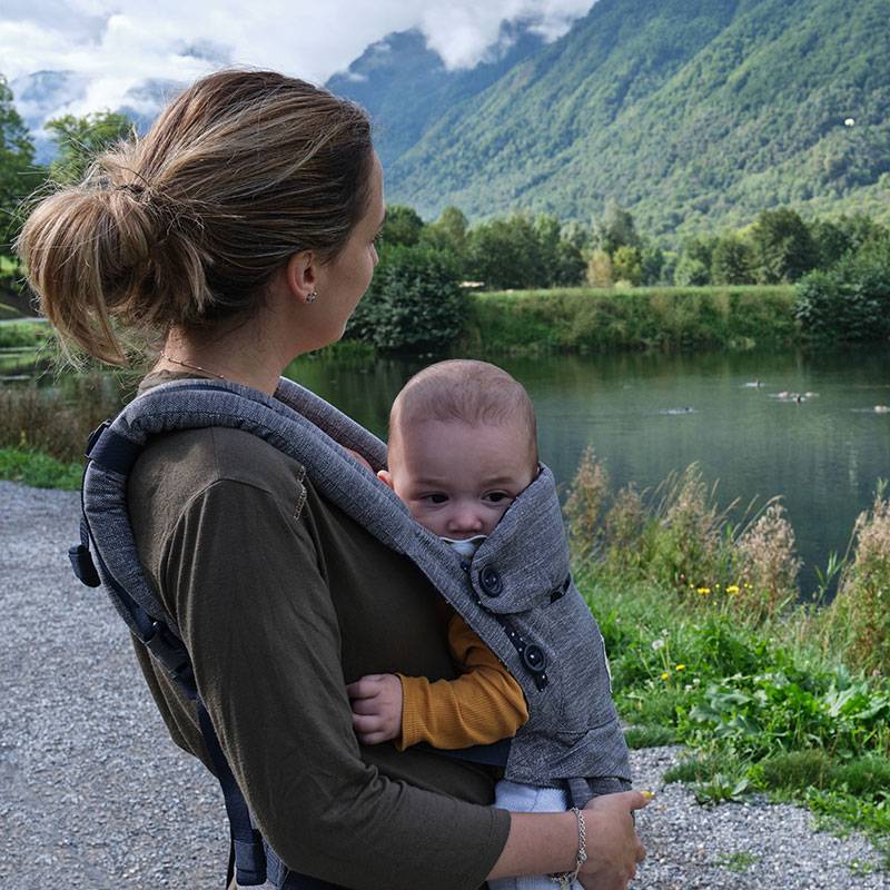 Mother with baby in a carrier outdoors.
