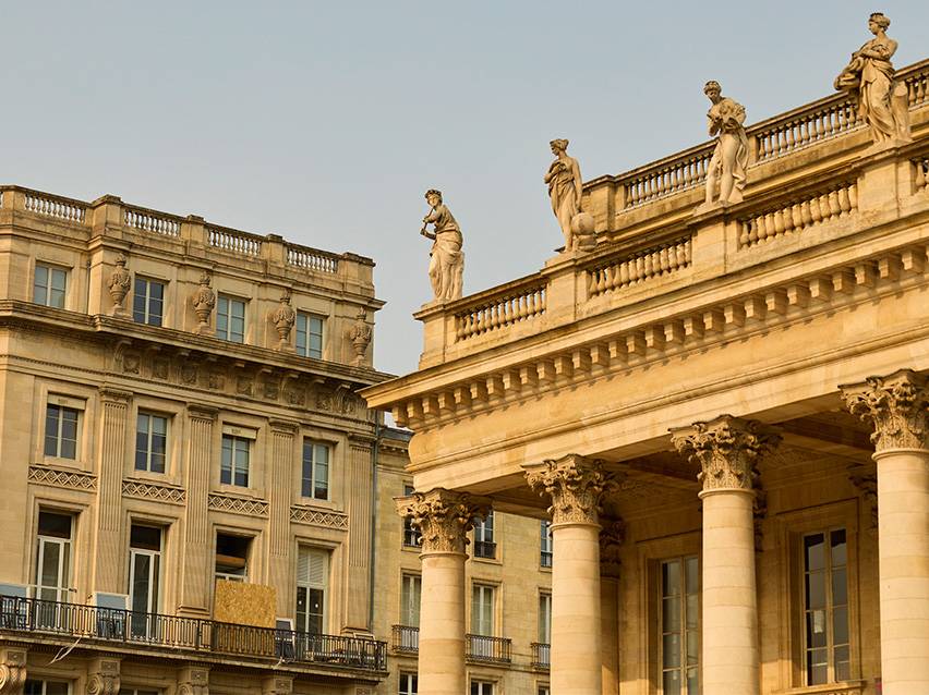 Historic building facade with rooftop statues and Corinthian columns.