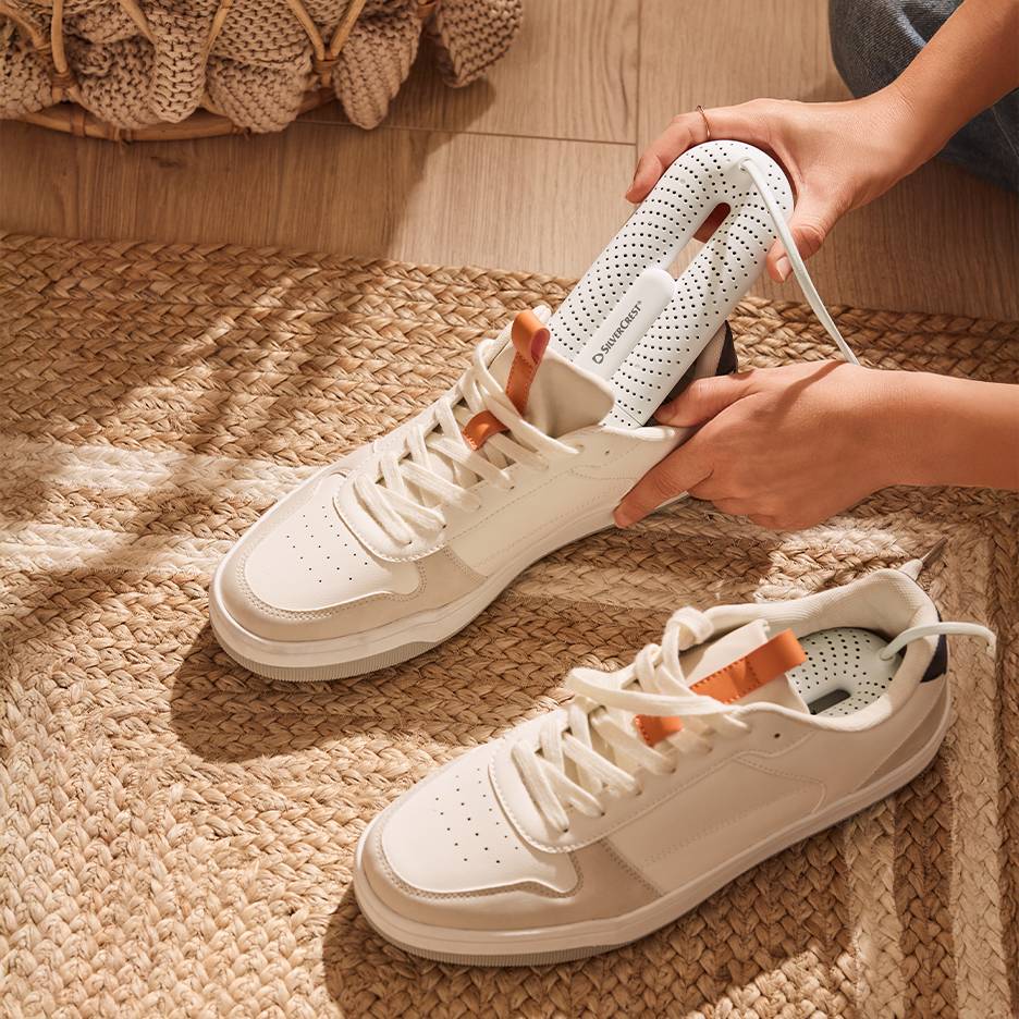 Silvercrest shoe dryer in white sneakers on a braided rug.