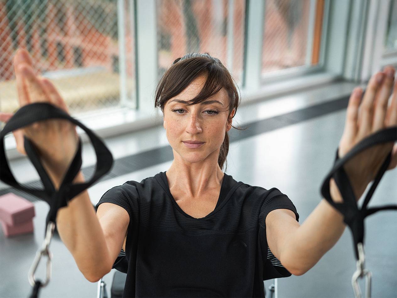 Woman exercising with resistance bands in a gym.