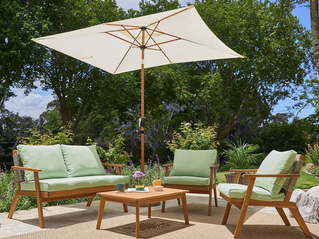Acacia wood garden furniture set with green cushions and a parasol.