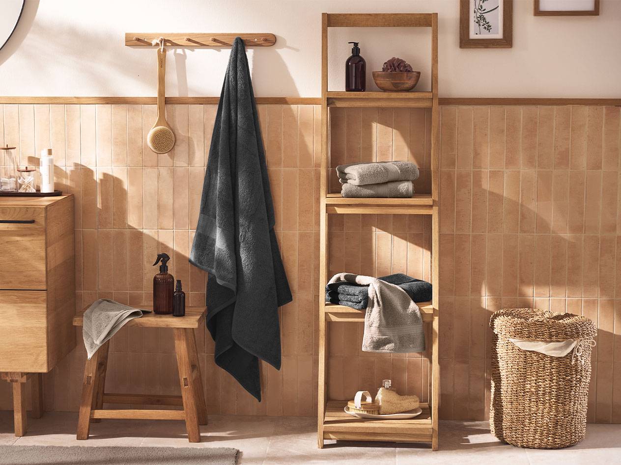 Bathroom with grey towels, wooden shelves, and bath accessories.