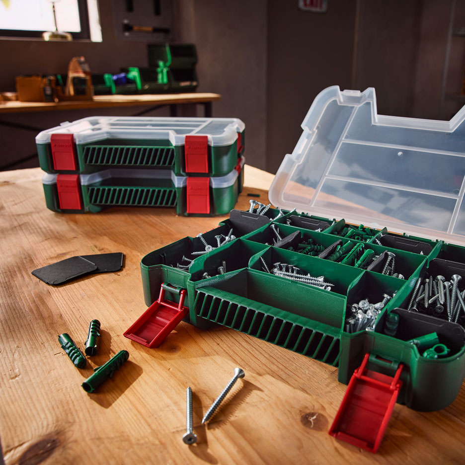Green tool organizers with screws and wall plugs on a wooden workbench.