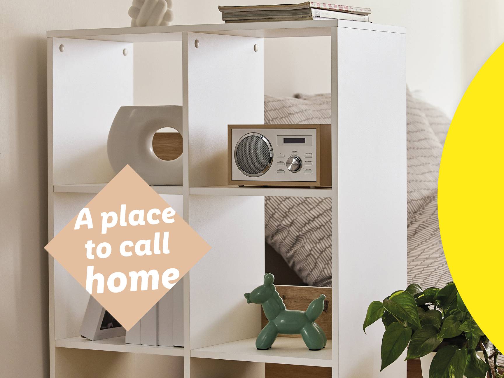 White cube storage unit with a radio, decorative items, and a plant.