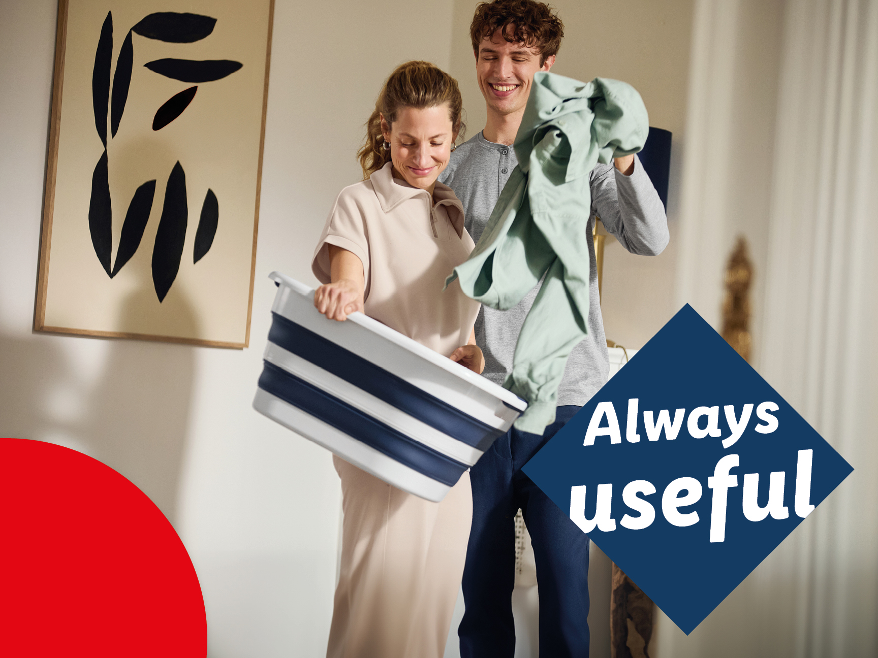 A couple folding laundry with a collapsible laundry basket.