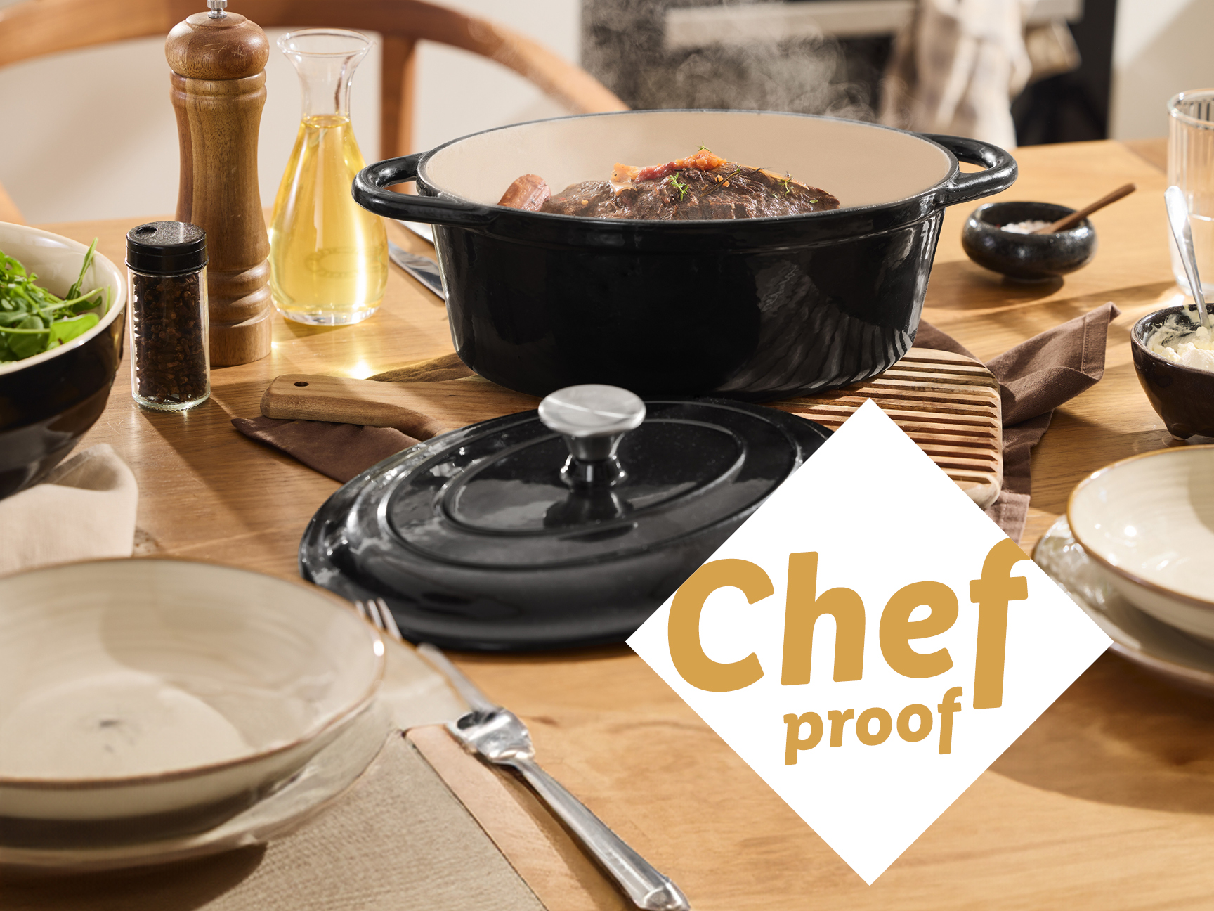 A black cast iron Dutch oven filled with food on a wooden table set for a meal.