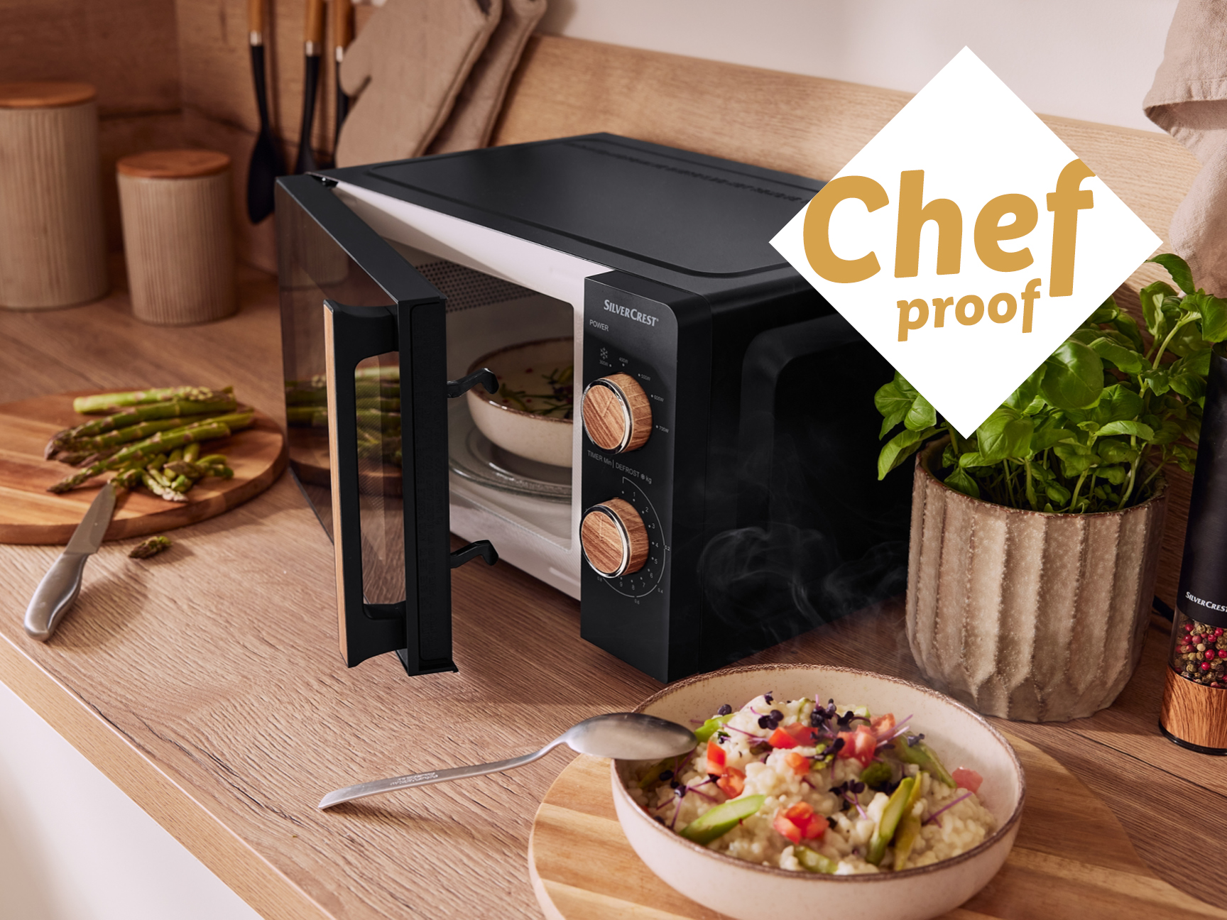 A black SilverCrest microwave with an open door on a wooden kitchen counter.