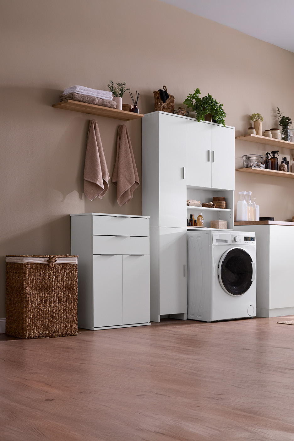 Laundry room with white cabinets, washing machine, wooden shelves, and a wicker basket.