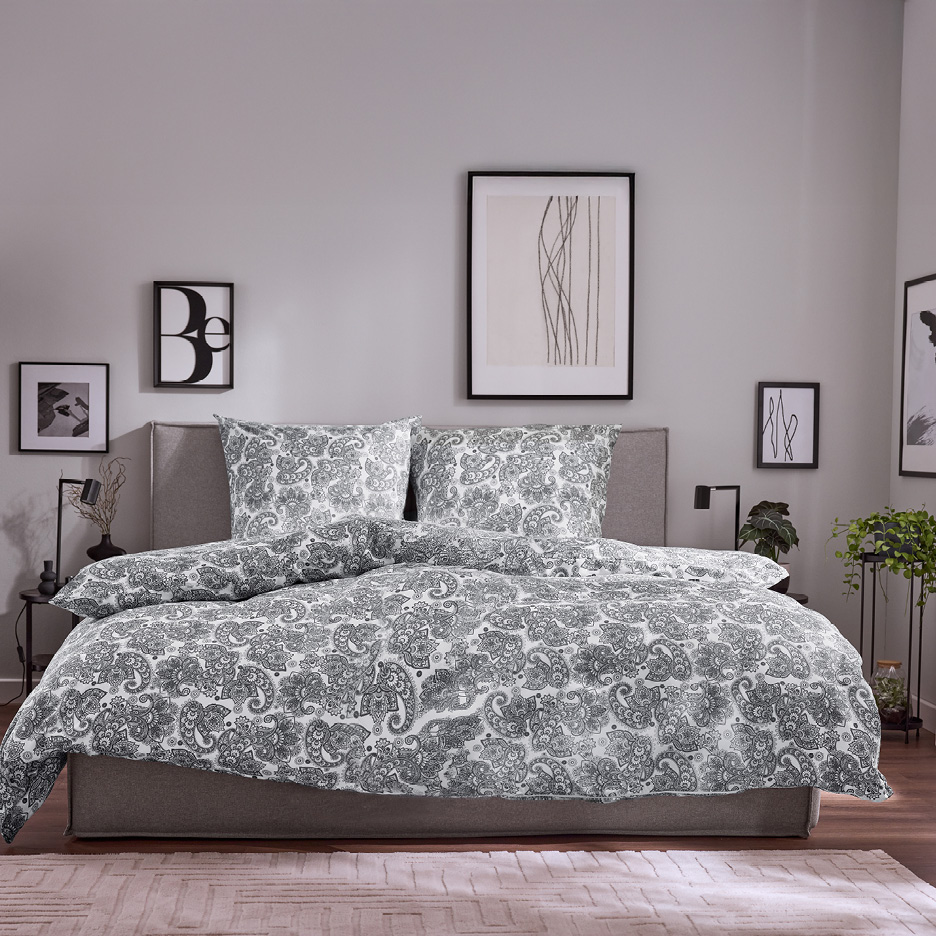 Bedroom with a bed featuring white and grey paisley patterned duvet cover and pillows.