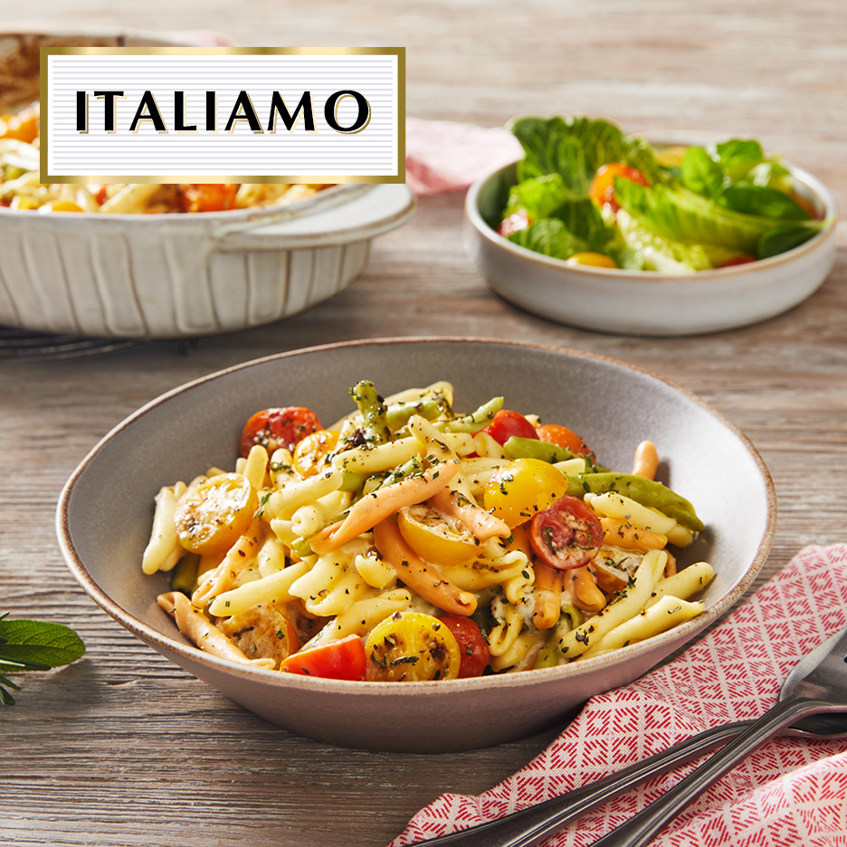 Italian pasta salad with colorful tomatoes and herbs, served with a side salad.