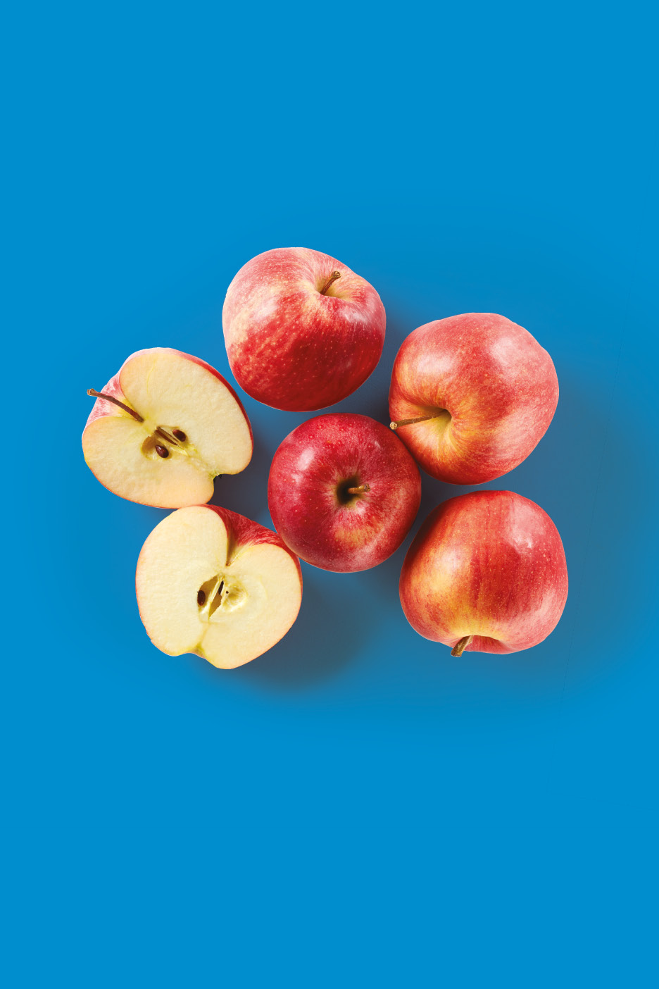 Red apples, some whole and some halved, arranged on a blue background.