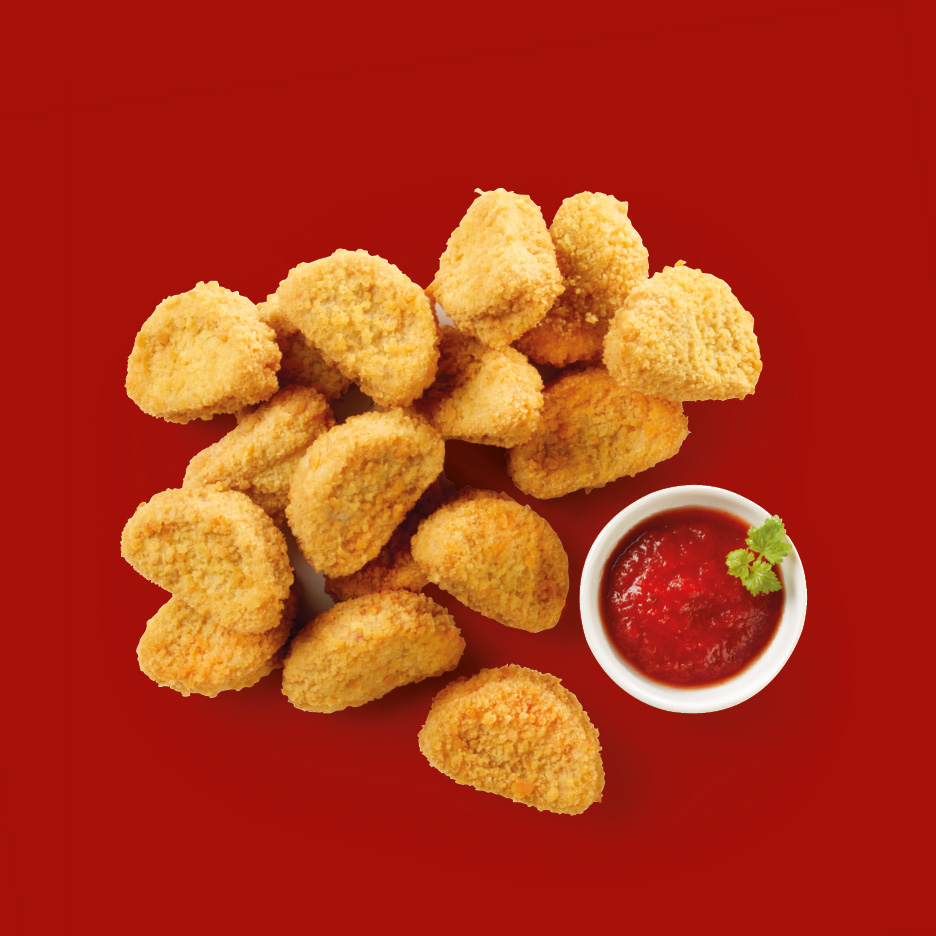 Crispy chicken nuggets with a side of ketchup and a sprig of parsley on a red background.