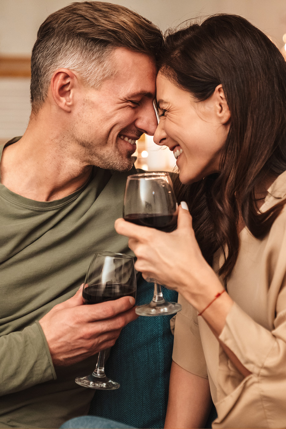 Happy couple toasting with red wine, enjoying a romantic evening together.