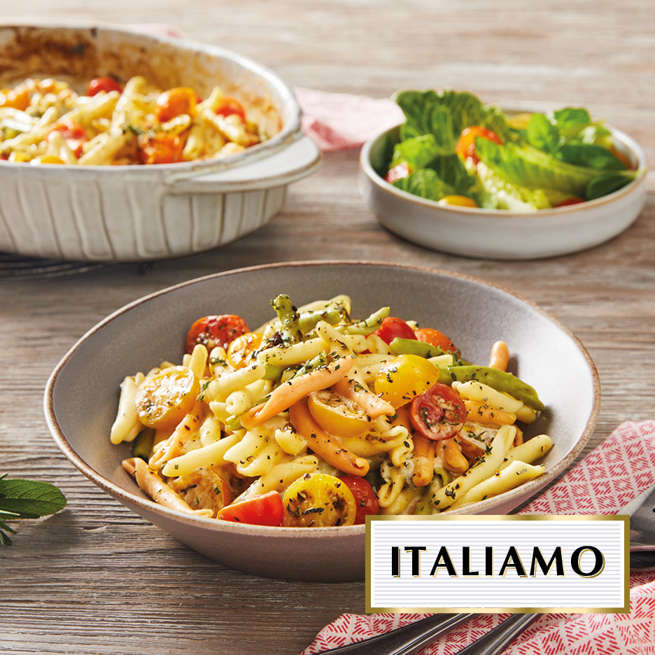 Pasta dish with cherry tomatoes and herbs, with a side salad and baking dish in the background. Text: ITALIAMO.