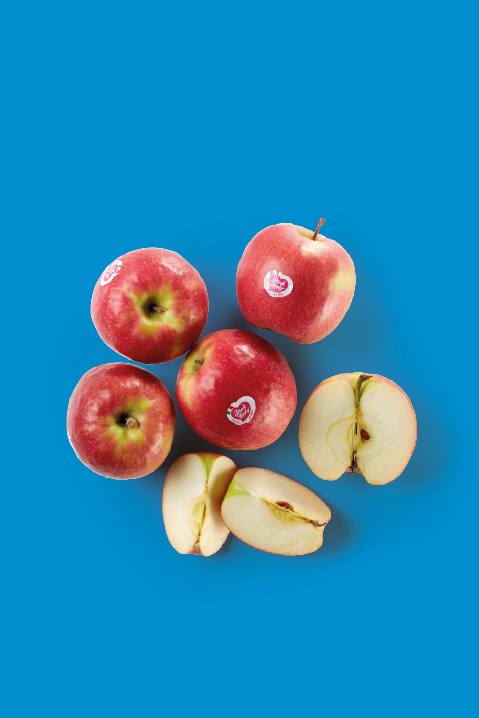 Red apples, some whole and some sliced, on a blue background.