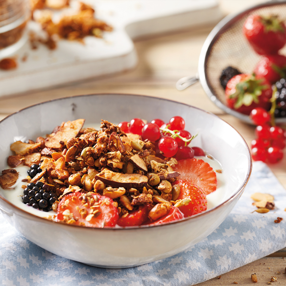 Granola with yogurt, strawberries, redcurrants, and blackberries in a bowl.