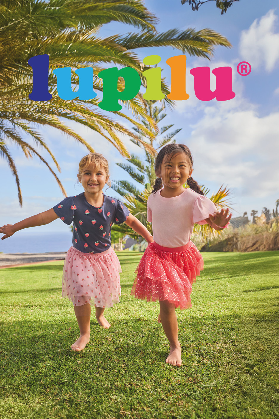 Two young girls in colorful children's clothing, including t-shirts and tutus, playing outdoors.