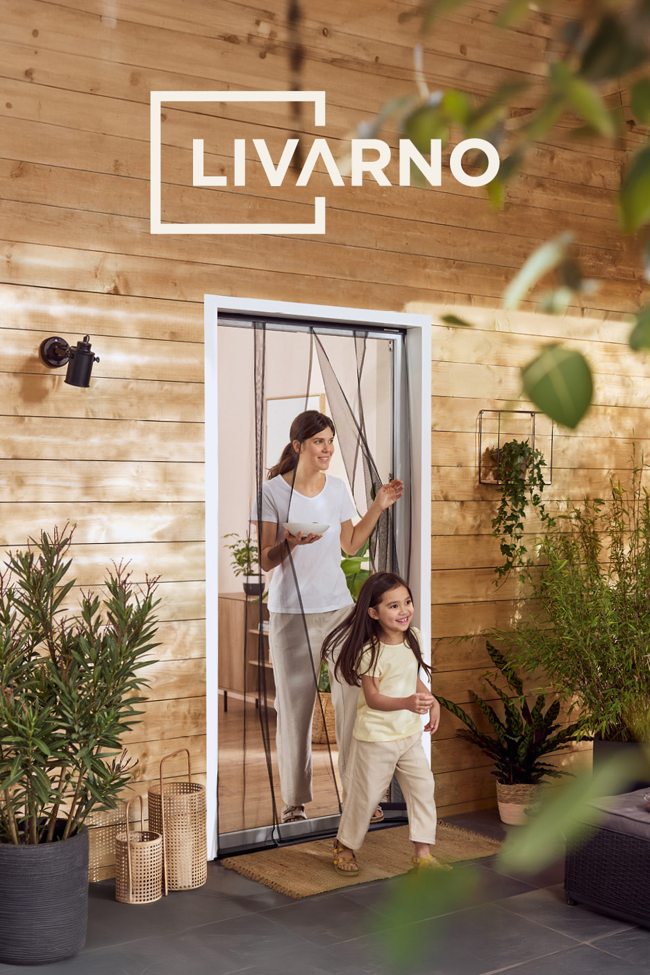 Woman and child exiting through a magnetic insect screen door onto a patio with wooden walls and plants.
