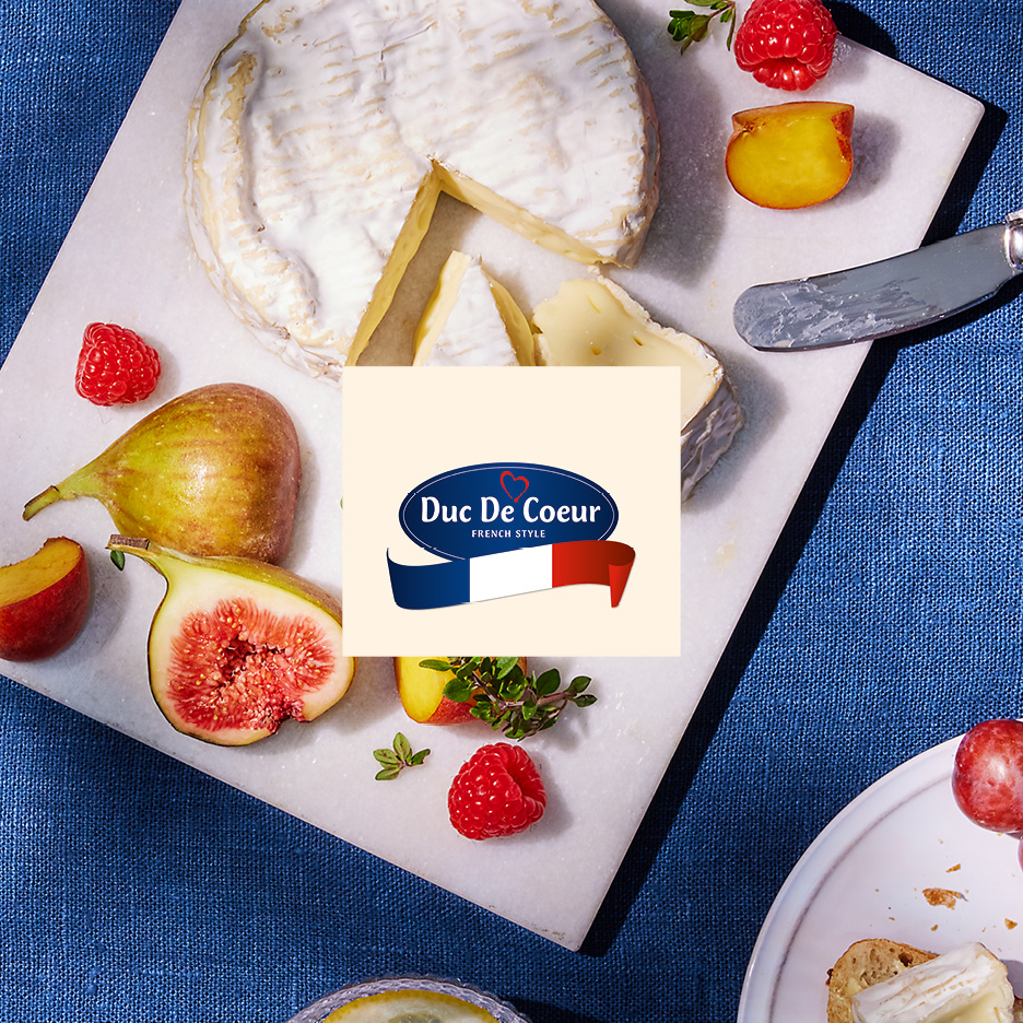 French-style cheese board with figs, raspberries, and peaches on a marble surface.
